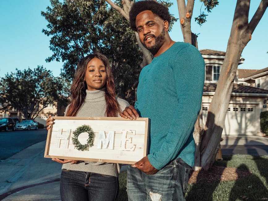 Smiling couple holding a 'Home' sign, symbolizing new beginnings in their neighborhood.