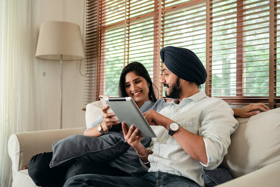Happy couple relaxing at home using a tablet and smartphone for leisure and communication.