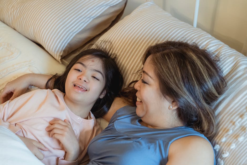 Mother and daughter enjoying a joyful moment while lying in bed, smiling together.