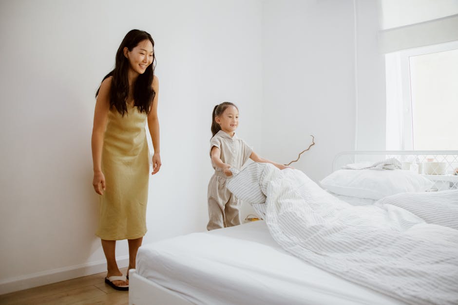 A mother and daughter happily making a bed, promoting family bonding.