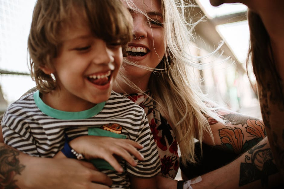 A mother and her young son share a moment of laughter in an outdoor setting, full of joy and connection.
