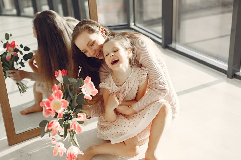 A loving mother and daughter duo laughing joyfully with a bouquet indoors.