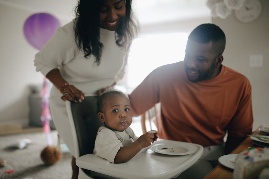 A joyful moment of parents with their baby celebrating a first birthday indoors.