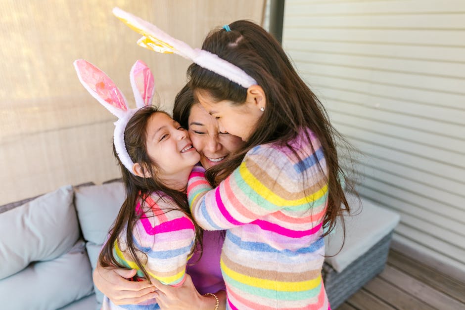 A mother embraces her daughters wearing colorful stripes and bunny ears, symbolizing warmth and love.
