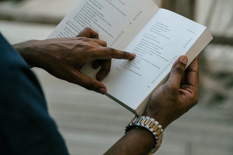 Close-up of a person reading an open book outdoors, capturing focus and inspiration.