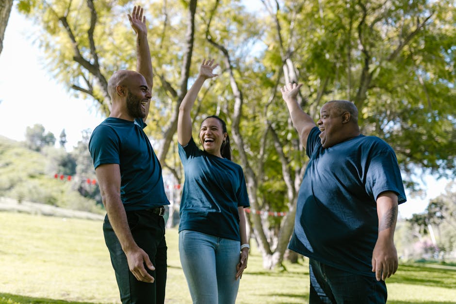 Group of diverse adults engaging in a joyful team building activity outdoors in a park.