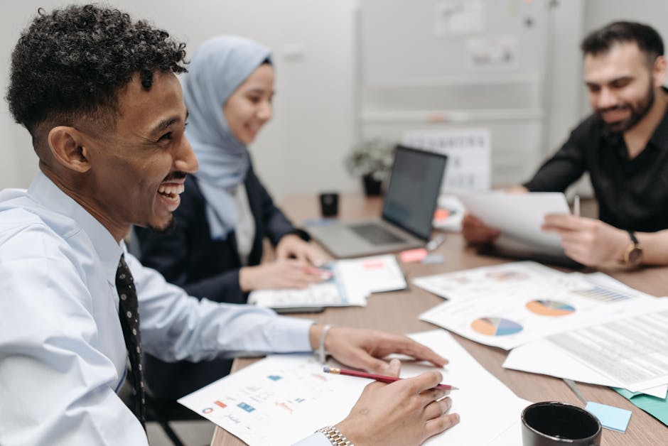 A diverse group of professionals working and laughing in a modern office setting.