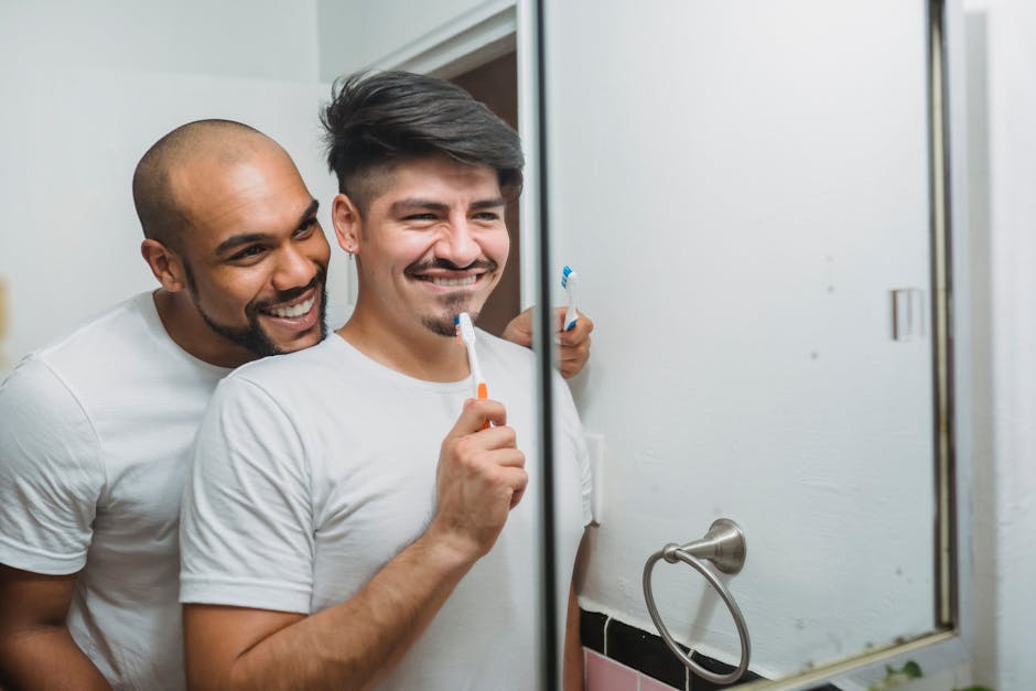 Two men in white shirts brushing teeth together, enjoying morning routine.