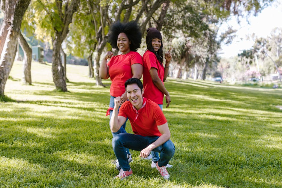 Three adults in red shirts enjoy a fun team building activity in a sunny park.