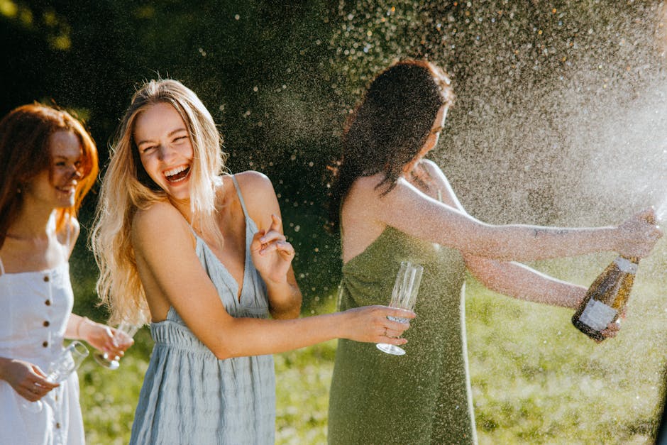 Three women enjoying a sunny day, laughing and celebrating with champagne outdoors.