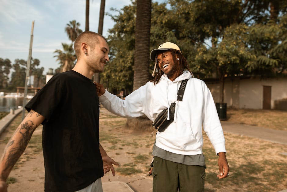 Two friends laughing and bonding outdoors in a sunny park, showcasing friendship and leisure.