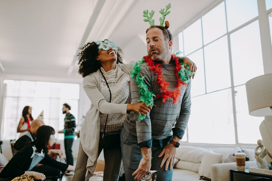 Joyful office holiday party featuring people in ugly Christmas sweaters having fun and laughing together.