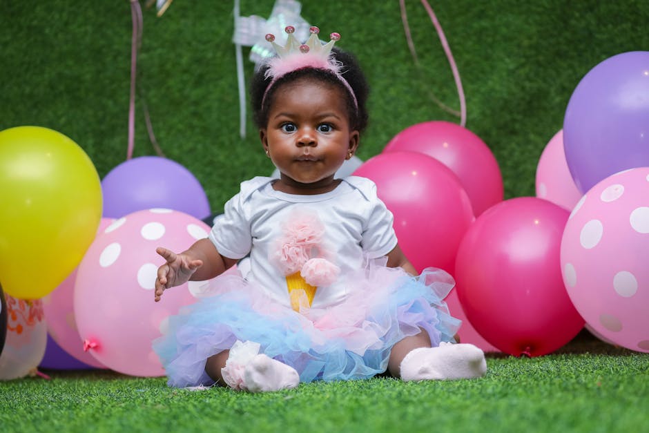 Cute baby girl enjoying a colorful birthday party with balloons.