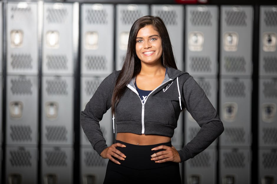 Smiling woman standing confidently in a gym locker room, ideal for fitness and lifestyle themes.
