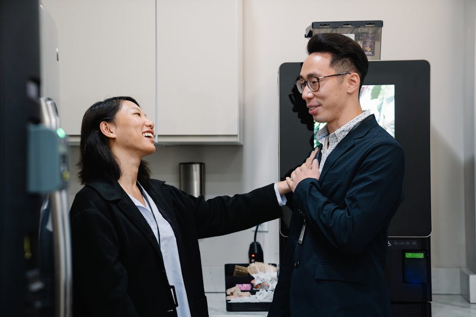 Two colleagues laughing and chatting during a break at the office.