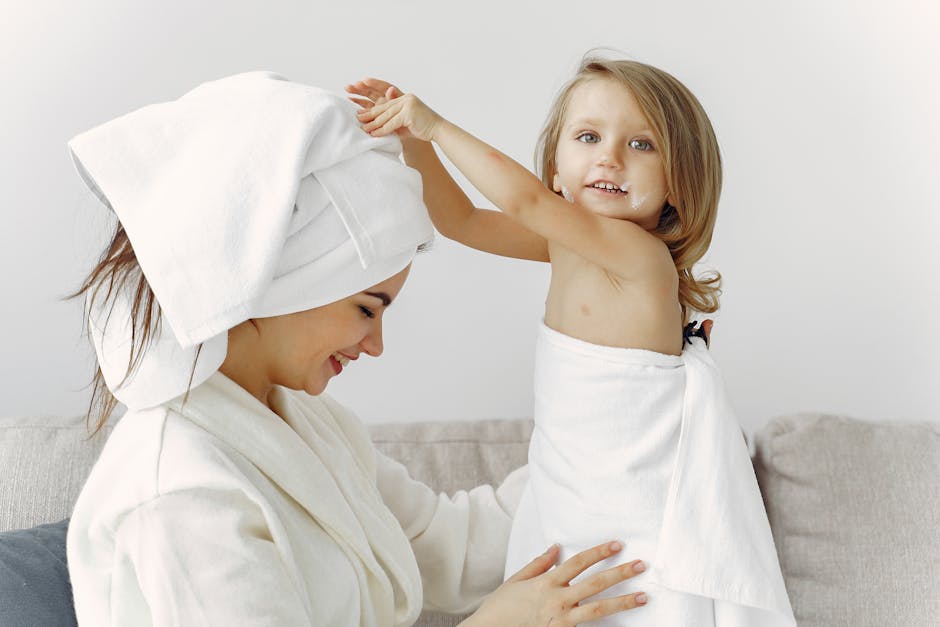 Joyful mother and daughter bonding indoors with towels wrapped around them.