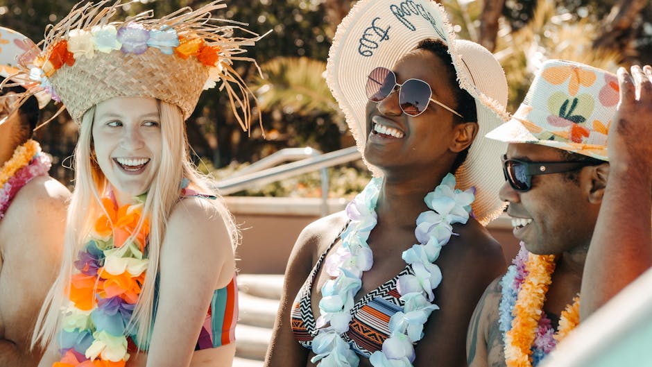 Group of friends enjoying a summer pool party with leis and sun hats.