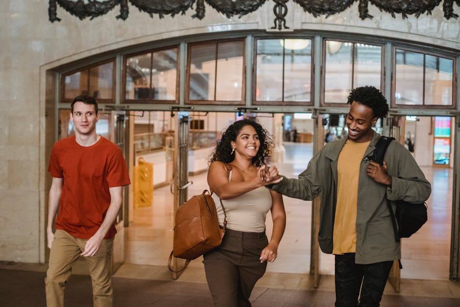 Three diverse friends joyfully walking through an indoor building, bonding and smiling.