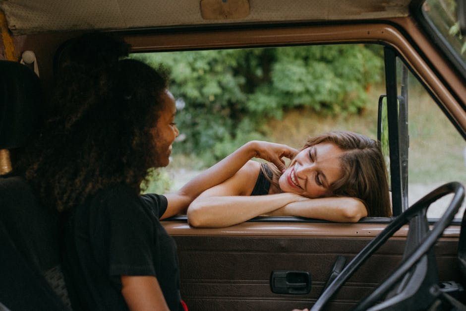 Two friends enjoying a carefree time together in a camper van during a summer road trip.
