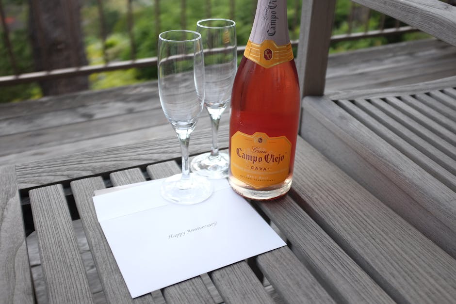 Celebrate your anniversary with champagne and glasses on an outdoor wooden table for a romantic occasion.