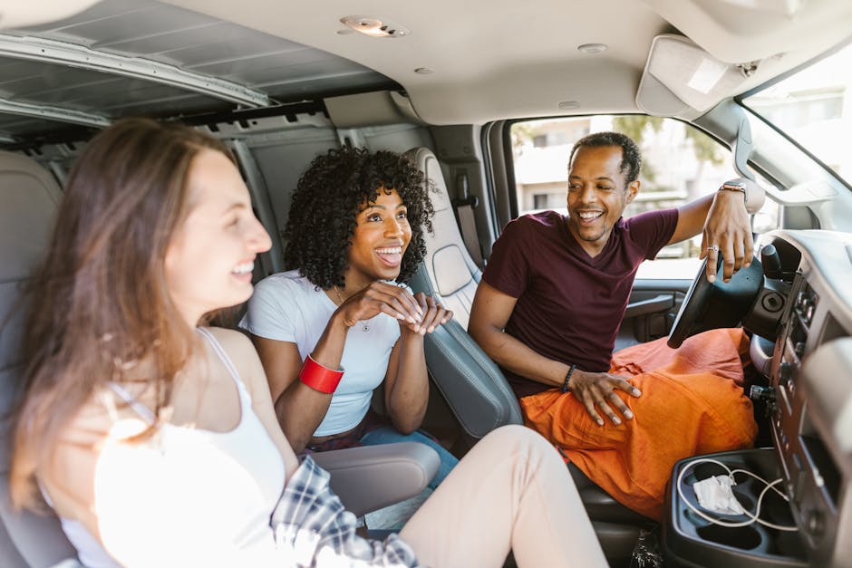Group of friends laughing and enjoying a road trip inside a van. Perfect for travel and lifestyle themed projects.