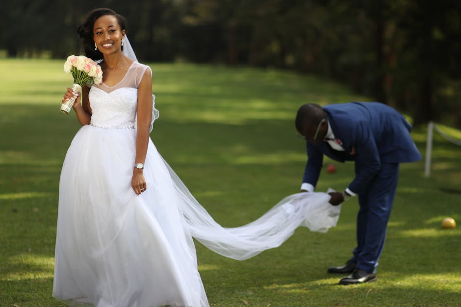 Bride in a white gown holding a bouquet outdoors, smiling with joy.