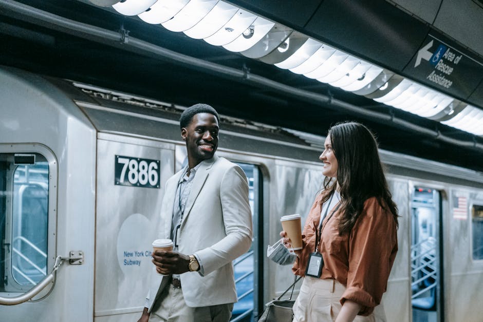A couple smiling and walking at a New York City subway station, holding coffee cups.