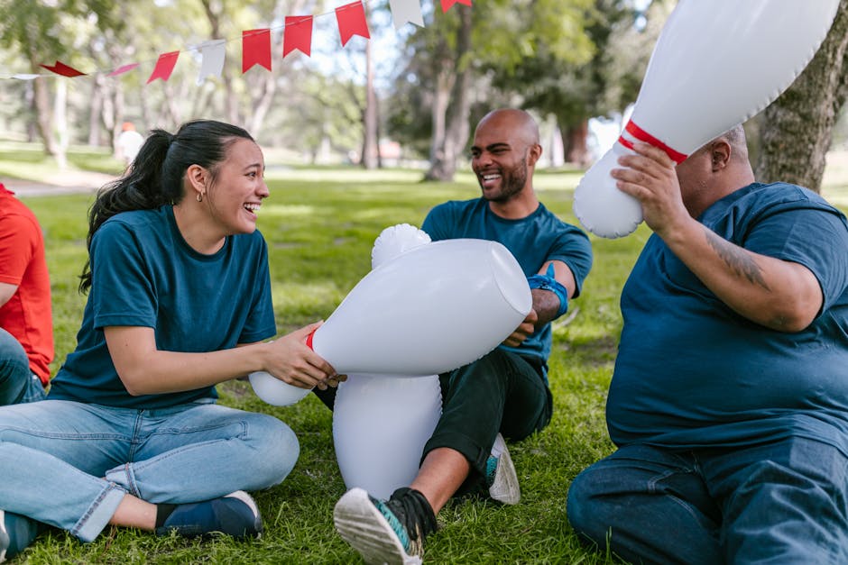 Group of adults enjoying a fun team building game with inflatable pins in a sunny park.