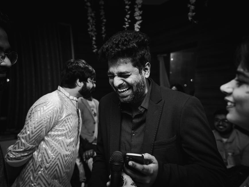 Adults laughing and enjoying at a party, capturing candid joy in a black and white image.