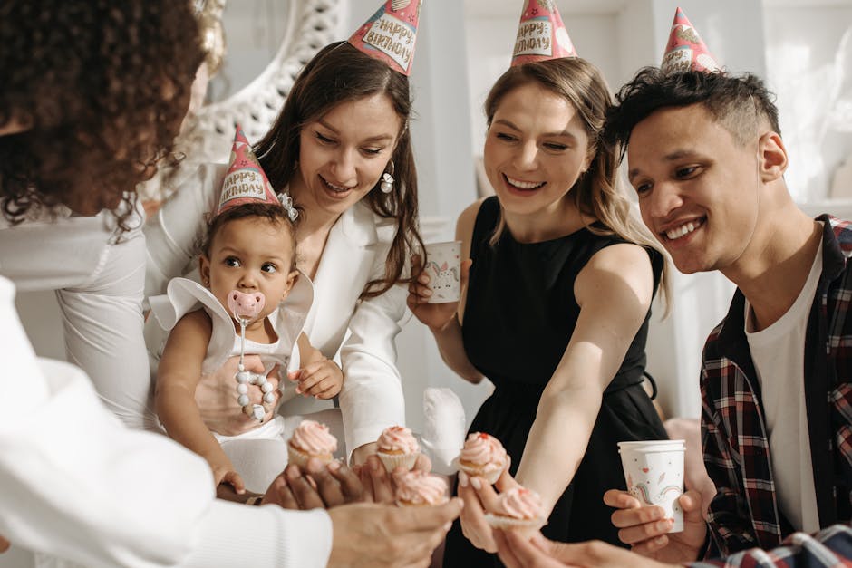 A joyful birthday celebration with friends and family sharing cupcakes indoors.