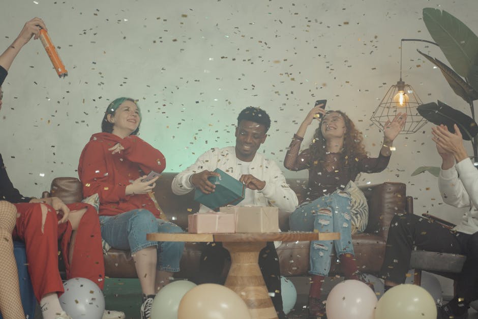 Group of friends celebrating indoors with gifts and confetti, creating a joyful atmosphere.