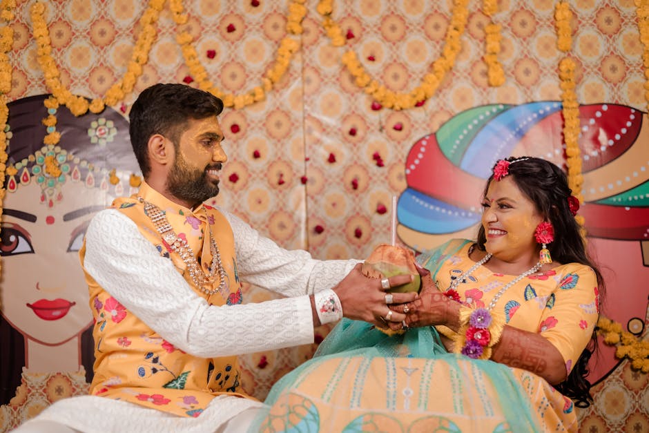 A cheerful Indian couple smiling and holding a coconut during a colorful wedding ceremony in Surat, India.