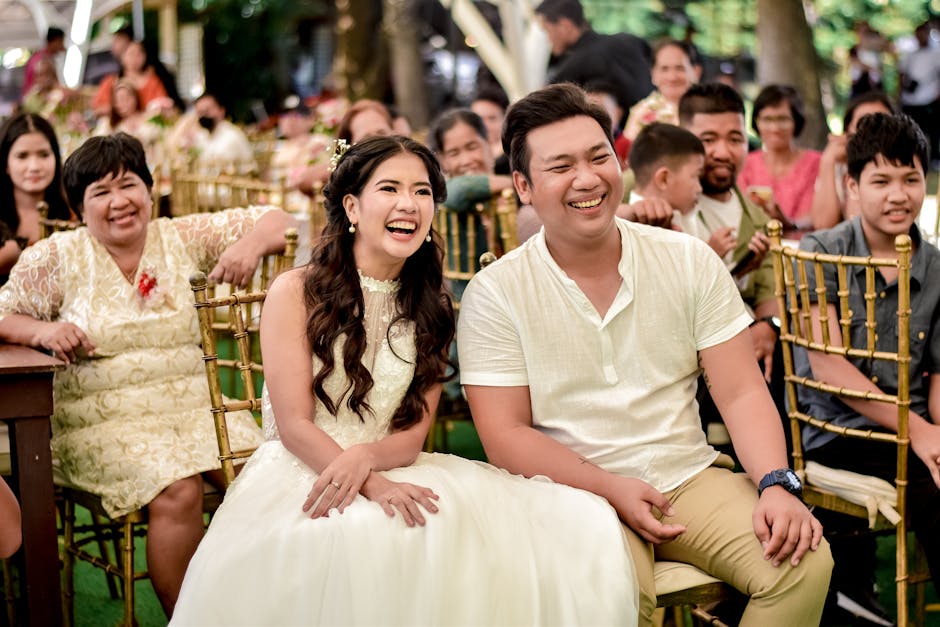 Happy couple laughing at an outdoor wedding ceremony surrounded by family and friends.