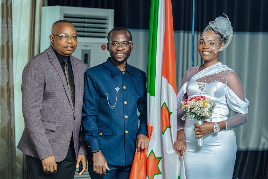 Joyful bride and groom posing with a friend at an indoor wedding ceremony.