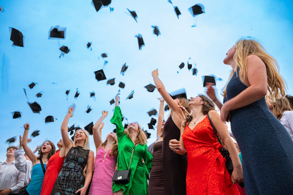 Group of graduates celebrating by tossing caps in the air against a bright sky.