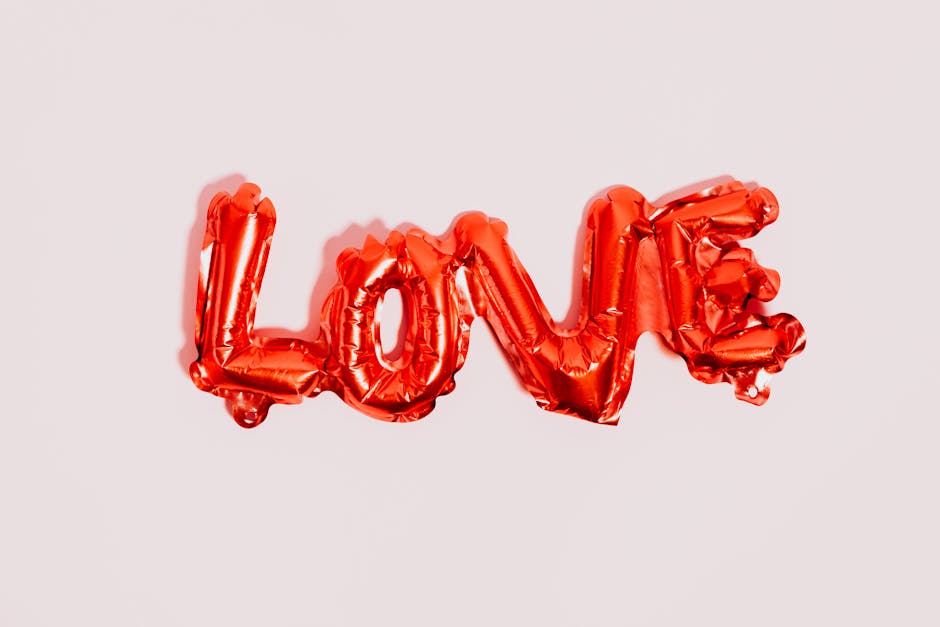 Bright red foil balloon spelling LOVE on a neutral background, perfect for celebration themes.