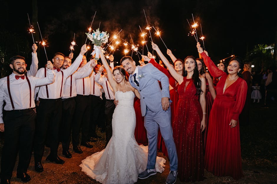 A beautiful wedding celebration at night with sparklers, featuring the bride, groom, and their party in elegant attire.