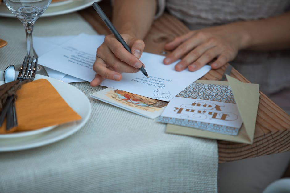 A person writing a Thanksgiving thank you note at a dinner table, surrounded by festive decor.