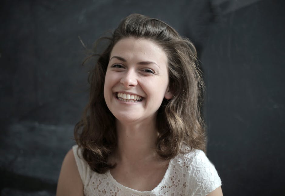 Portrait of a cheerful woman with a radiant smile against a dark backdrop.