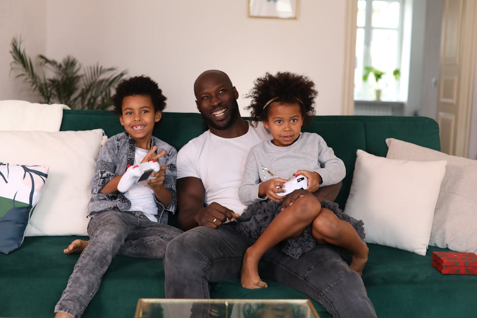 Smiling father with children enjoying video games on a cozy living room sofa.