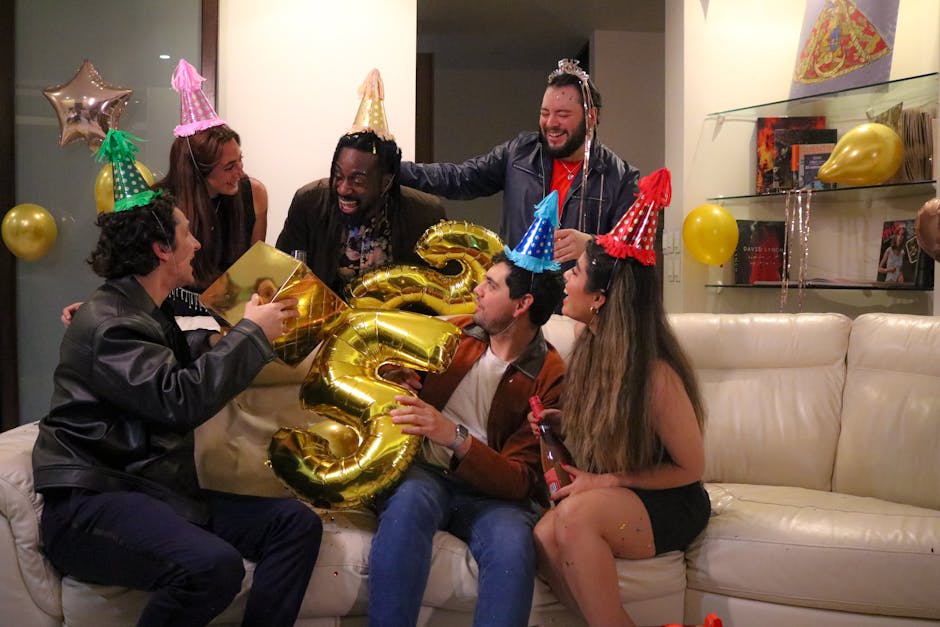 Group of friends celebrating indoors with party hats and golden balloons.