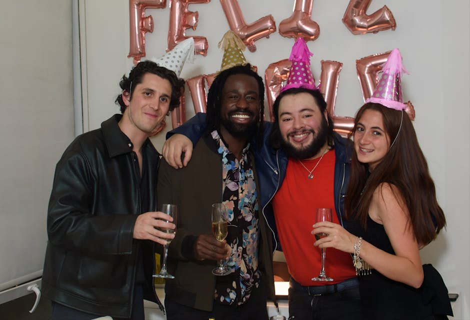 Four friends celebrating with party hats and champagne indoors.