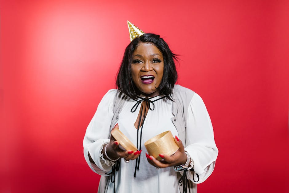 A cheerful woman celebrating with party accessories against a vibrant red background.