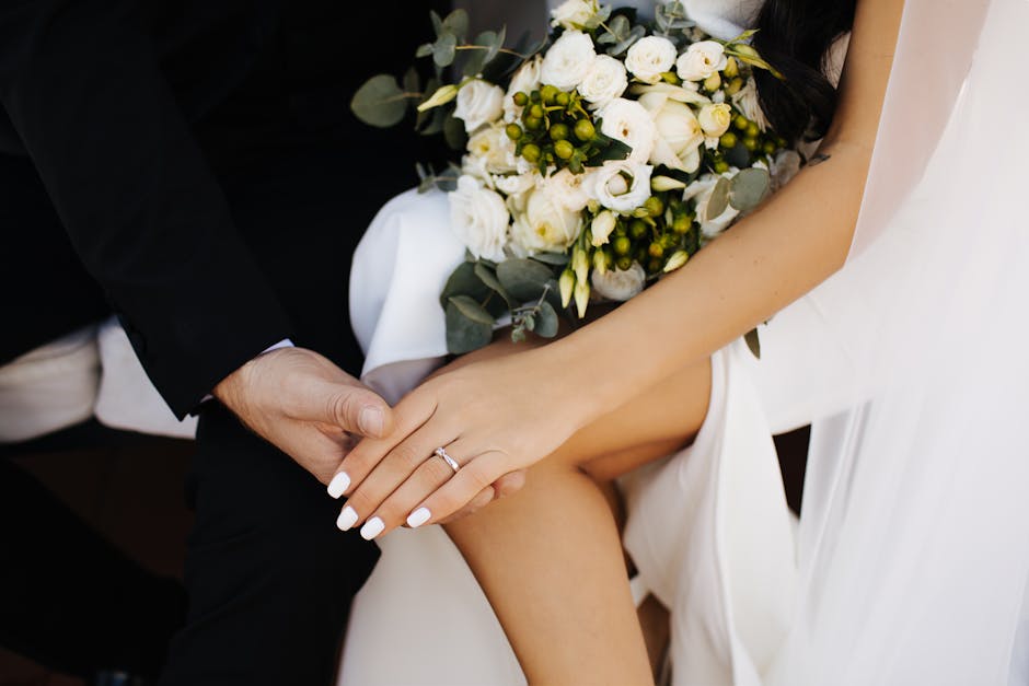 Close-up of bride and groom's hands with floral bouquet, capturing romantic essence of wedding day.