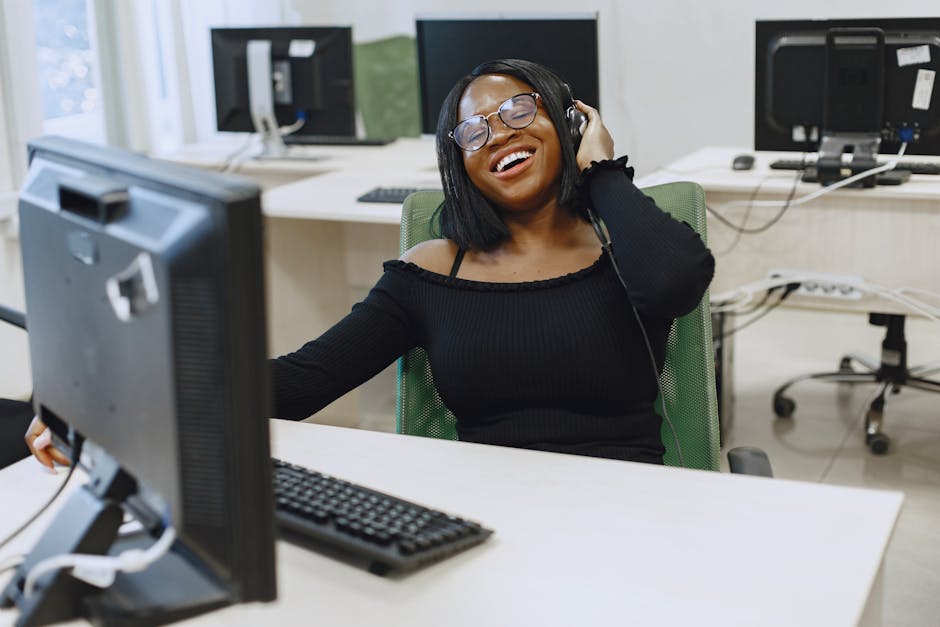 Smiling woman wearing headset and glasses, enjoying work at office desk.
