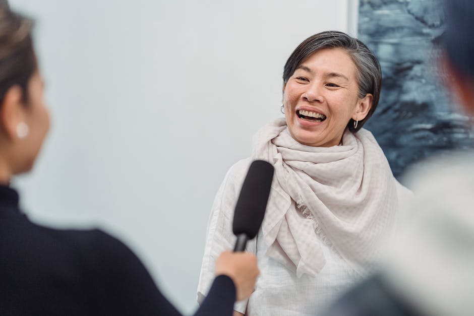 A joyful woman being interviewed with a microphone, smiling and laughing.