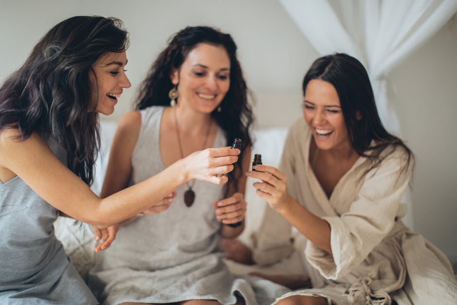 Three women joyfully engaging in aromatherapy indoors, emphasizing relaxation and laughter.