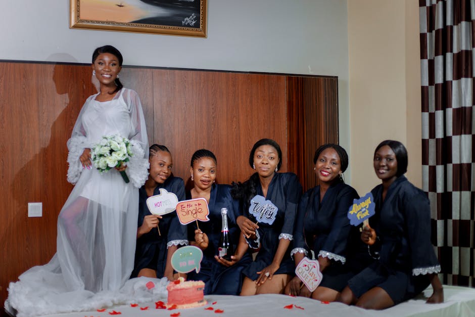 Joyful bridal party posing in a hotel room with signs and champagne.