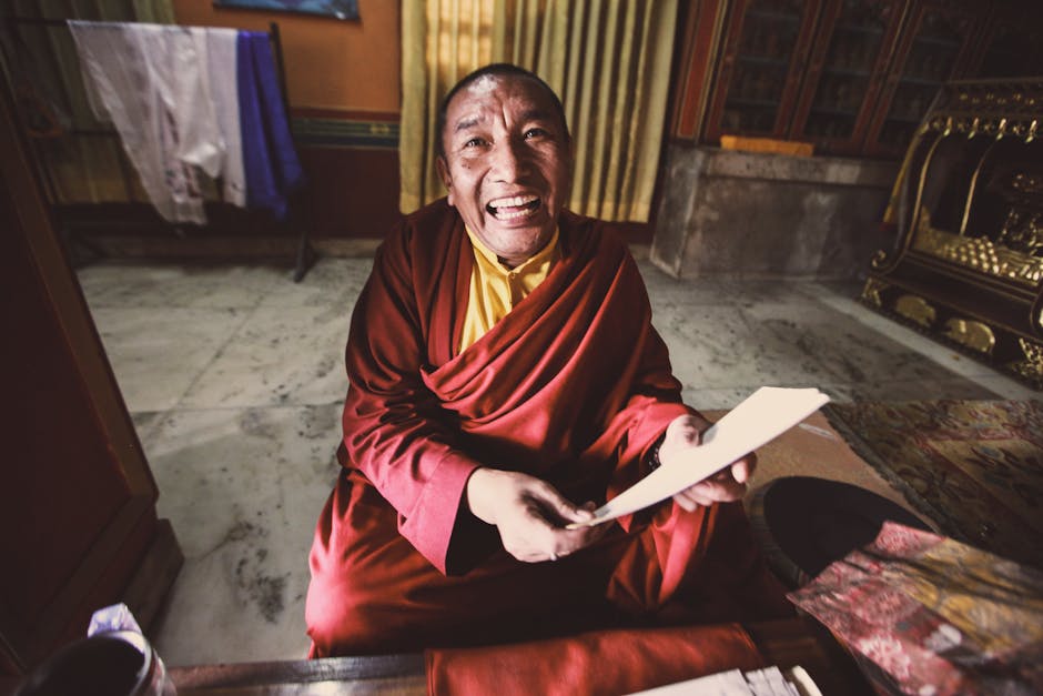 A Buddhist monk joyfully reading a letter while sitting indoors, dressed in traditional kasaya robes.