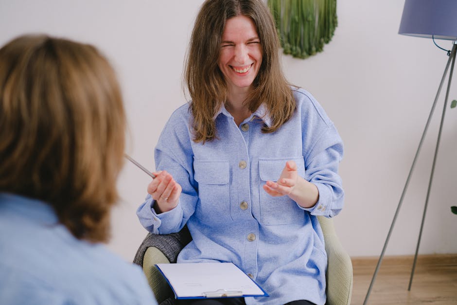 A woman laughing while having a casual meeting indoors, holding notes.